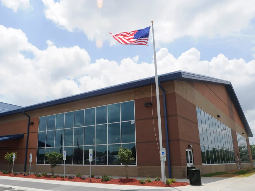 Contemporary Civic or Commercial Building Modern brick and glass building with an American flag waving in front under a partly cloudy sky.